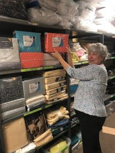 A volunteer is adding new sheets to our linen inventory recently depleted.
